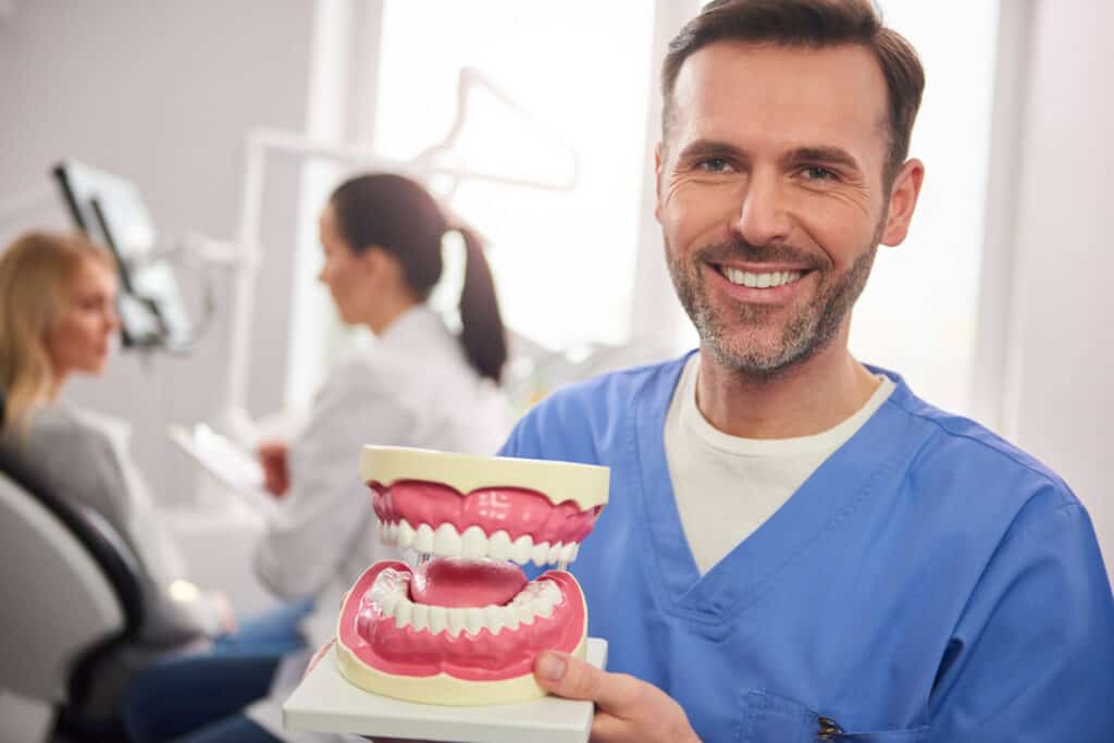 Dentist Smiling While Showing Prototype Teeth