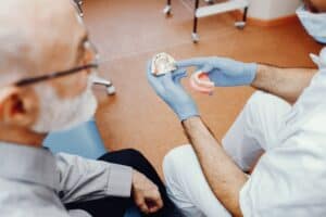 Dentist Teaching Old Man How To Clean Dentures