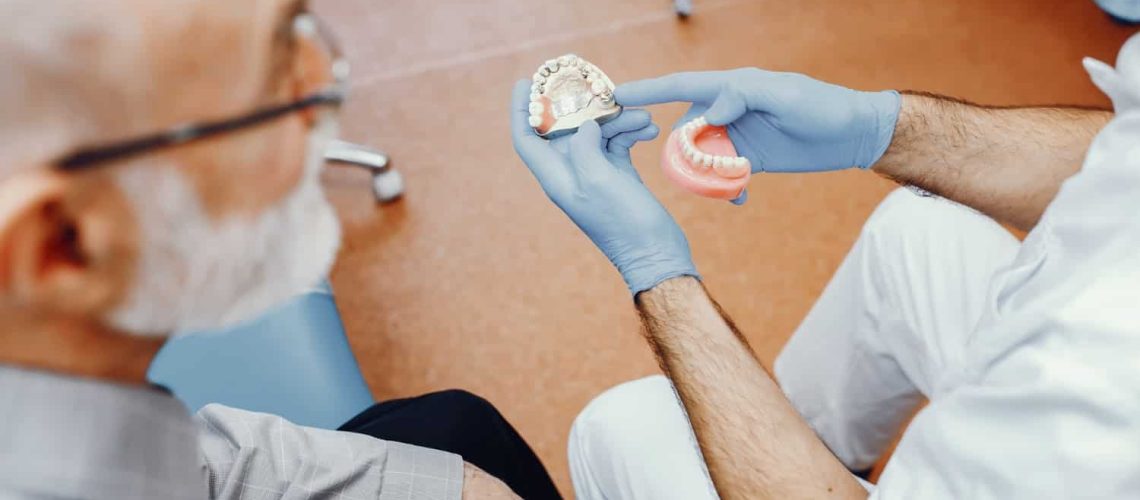 Dentist Teaching Old Man How To Clean Dentures